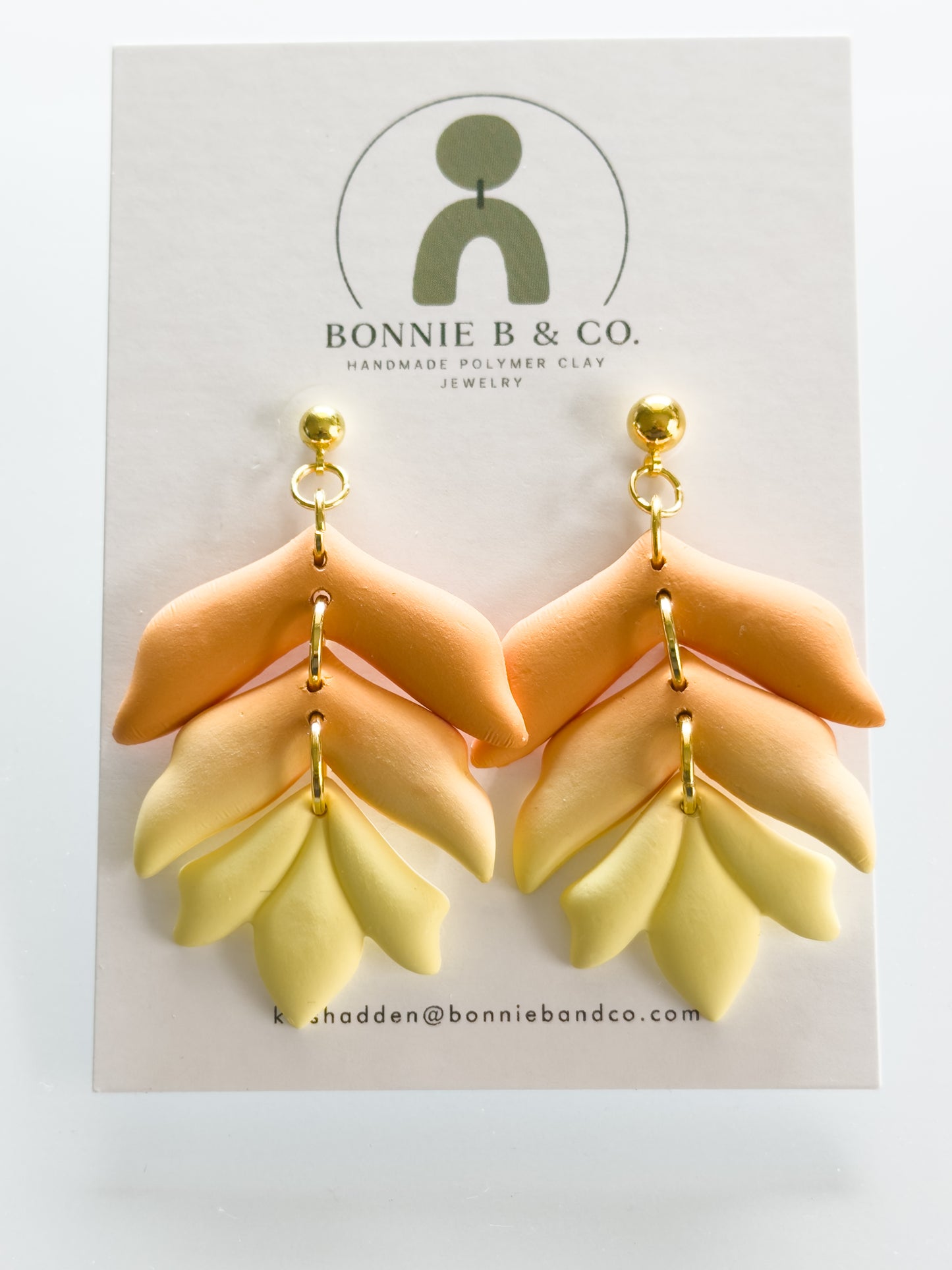 Handmade polymer clay dangle earrings in a warm sunset gradient, featuring layered terracotta and soft yellow tones in a boho style