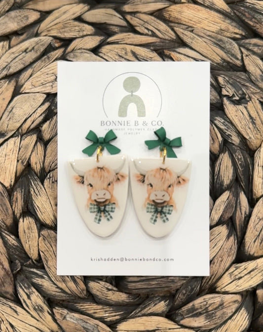 Handmade polymer clay cow earrings with green bow