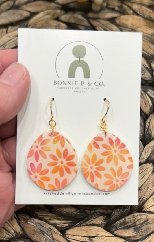 Marigold Teardrops handmade floral polymer clay earrings with warm orange and pink flowers on a translucent base, displayed on a Bonnie B & Co earring card