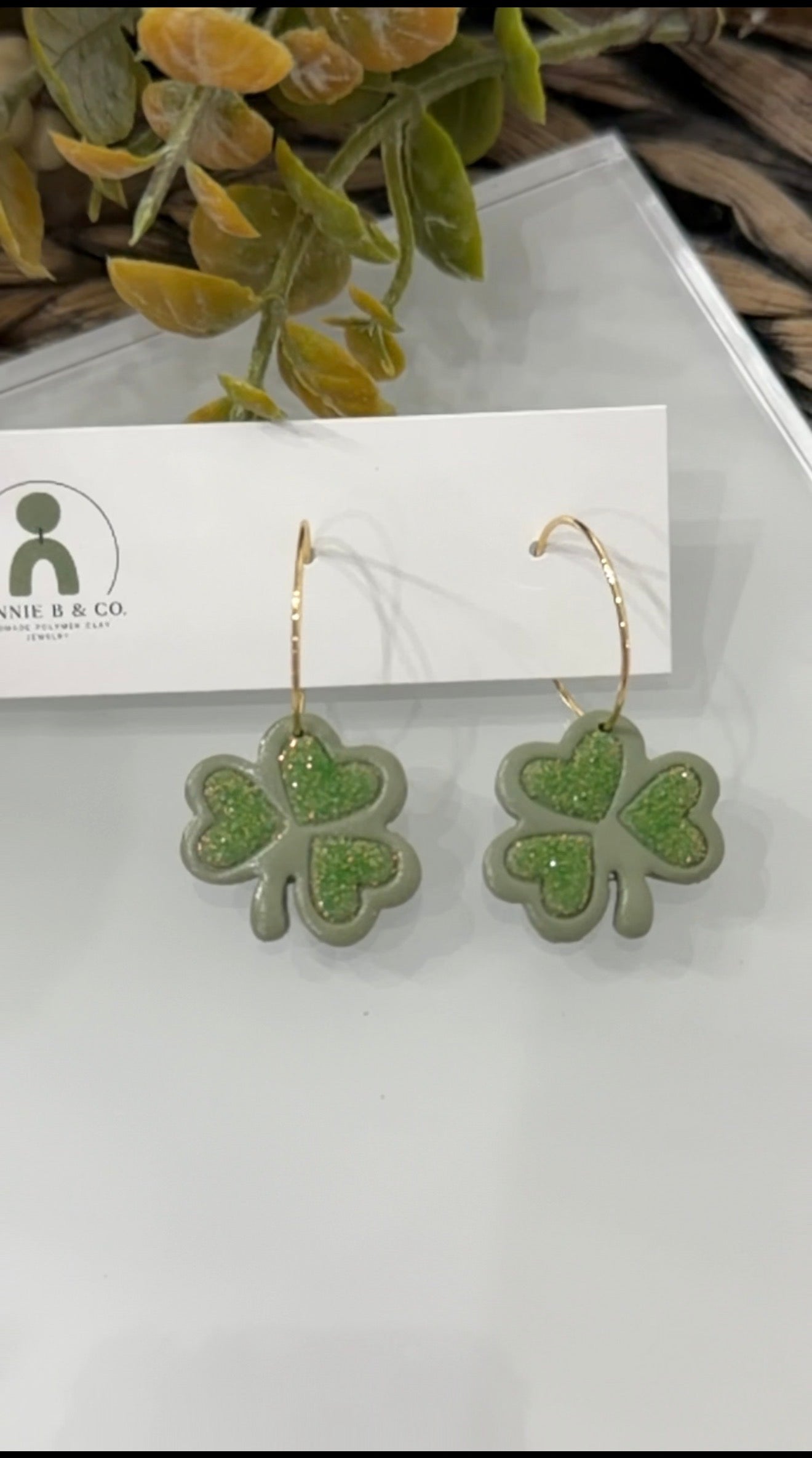 Handmade shamrock polymer clay earrings with sparkly green center on gold hoop earrings