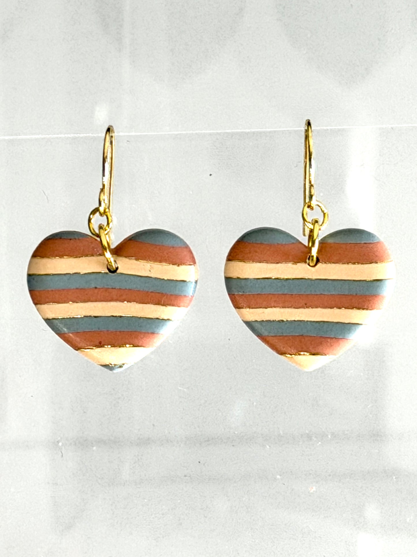 Painted Desert heart dangle earrings with soft striped polymer clay in turquoise, terracotta, and sand tones with gold accents on gold hooks
