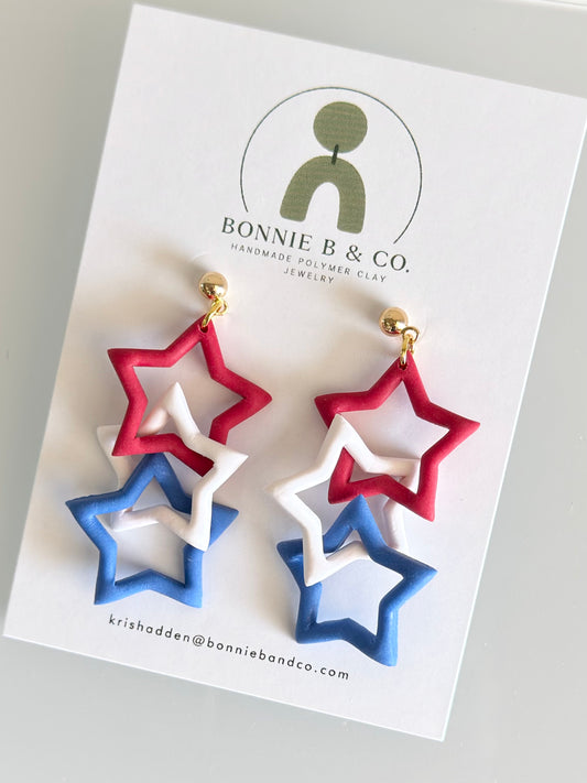 Red white and blue patriotic star polymer clay dangle earrings with gold hardware on Bonnie B & Co display card