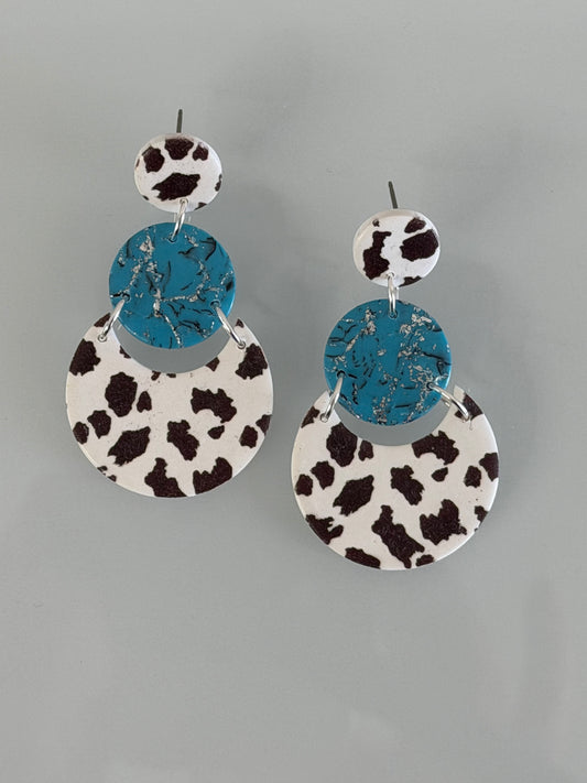 Handmade western polymer clay earrings featuring turquoise texture, cow print design, and titanium posts.