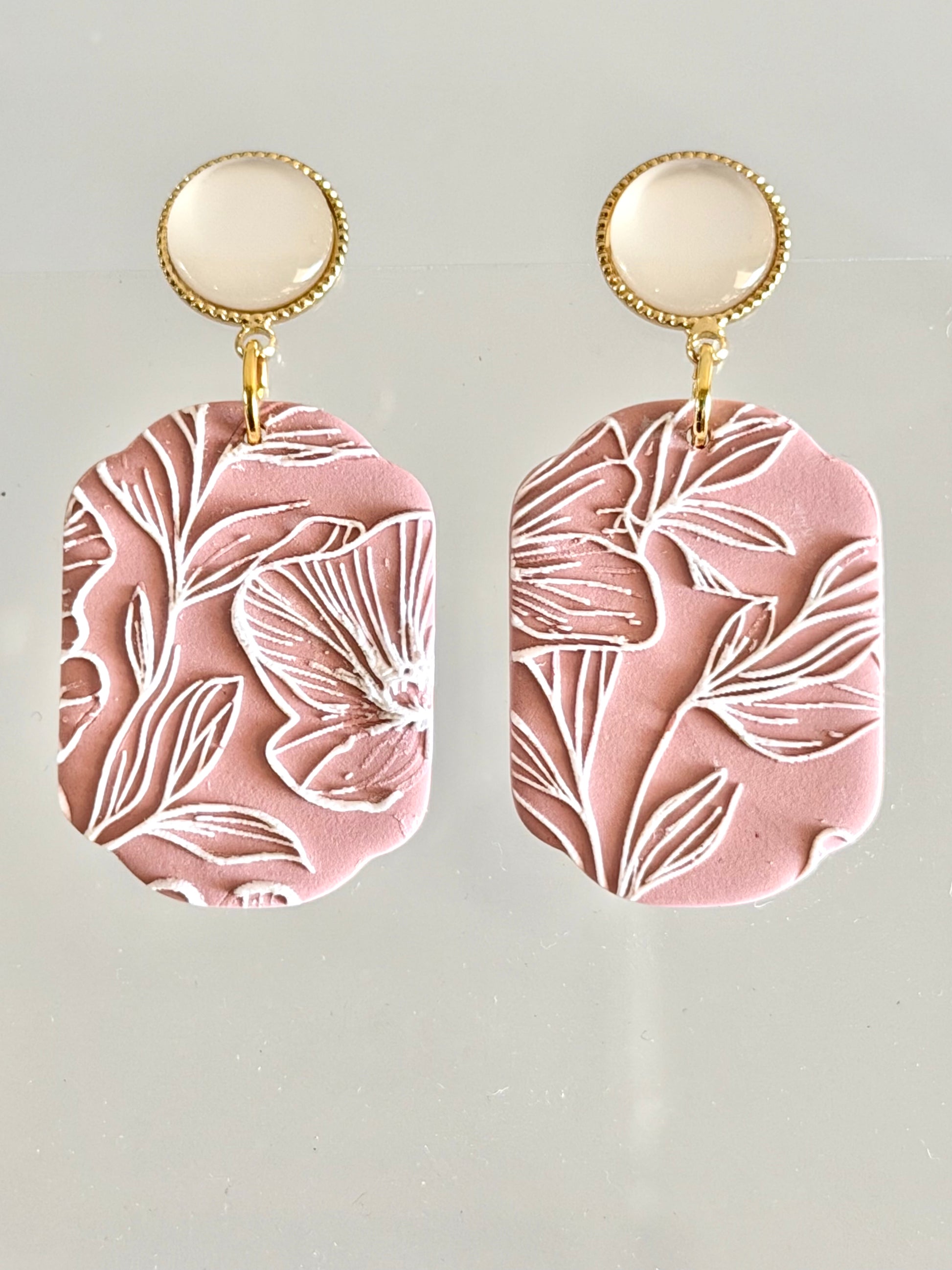 Handmade dusty rose polymer clay earrings with white floral carved design and gold accents