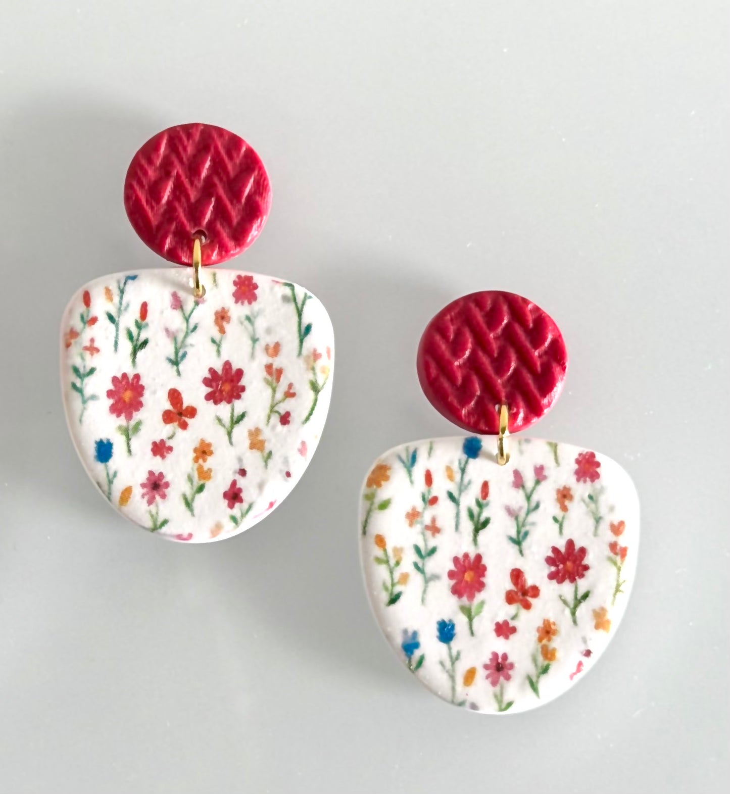 Handmade polymer clay earrings with colorful wildflower design and textured berry red
 stud tops