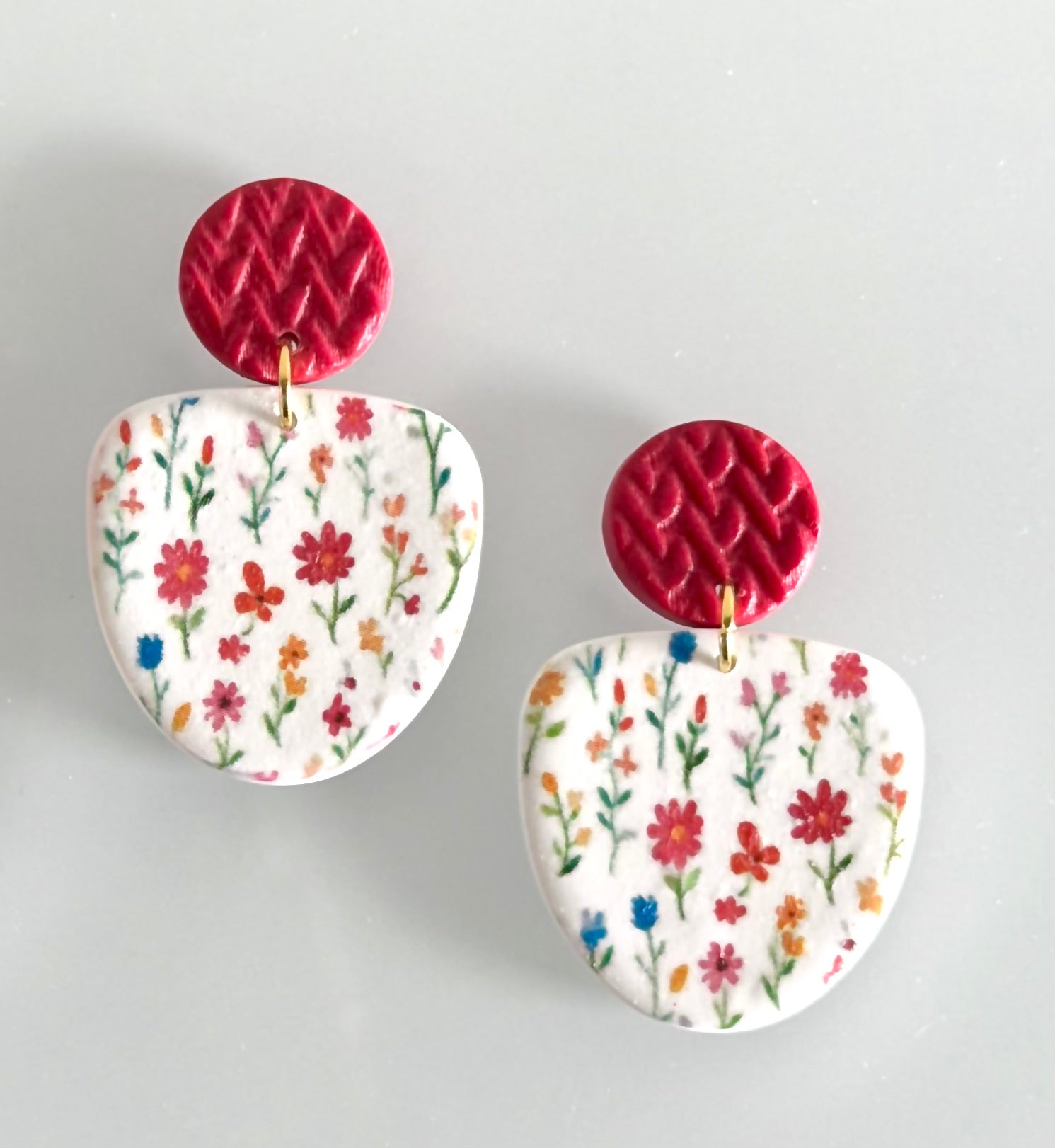 Handmade polymer clay earrings with colorful wildflower design and textured berry red
 stud tops